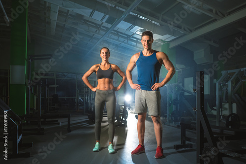 The sport couple stand in the modern gym on the bright light background