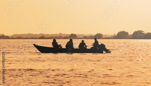 Fotografie Landscape at sunset of a boat with fishermen fishing on Pantanal