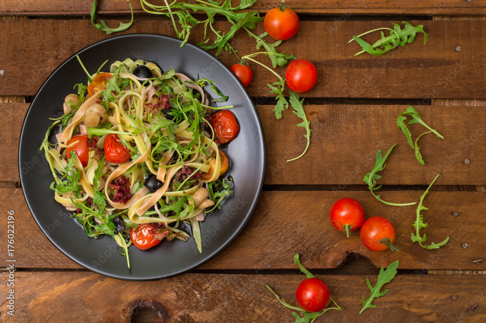 Italian bucatini with shrimp, arugula and cherry tomatoes. Wooden background. Close-up. Top view Italian bucatini with shrimp, arugula and cherry tomatoes. Wooden background. Close-up. Top view