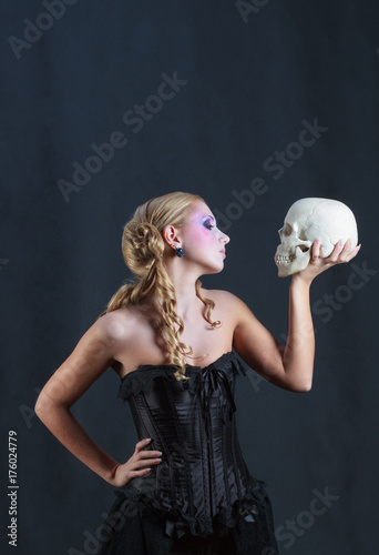 Beautiful woman in black corset with a skull