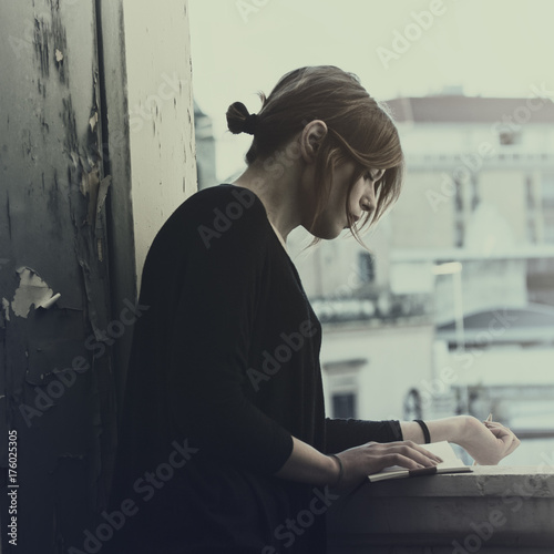 Pretty girl reading a book on the balcony