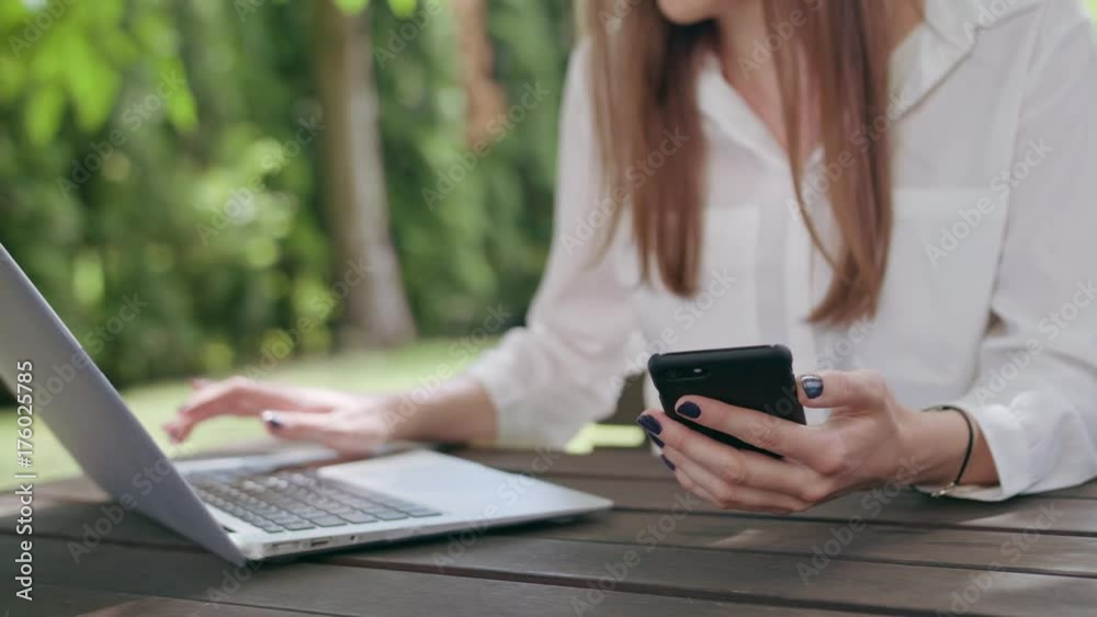 Business lady using a laptop and a phone. Close-up shot. Soft Focus