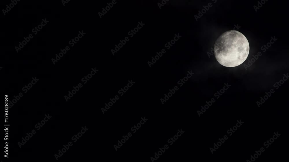 Full moon at night on dark black sky behind moving clouds, moonlight 4K ProRes HQ codec