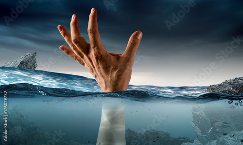 Hand of person drowning in water photo