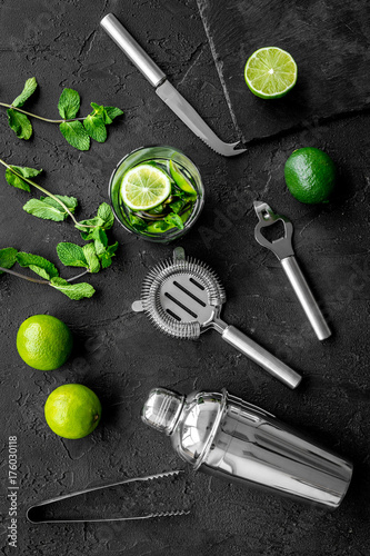 In the bar. Shake mojito. Lime, mint., barman tools on black background top view