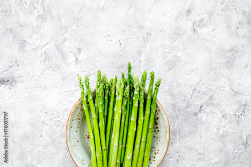 Sprouts of fresh asparagus on grey stone background top view copyspace