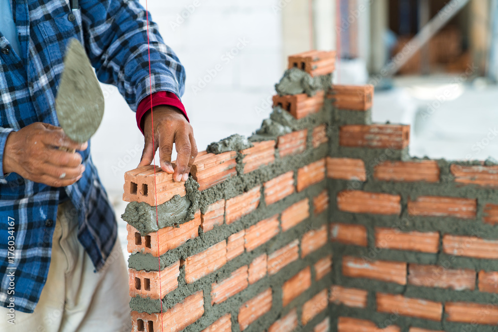 Construction worker build home by use cement mortar  to lay brick wall with a trowel follow vertical and horizontal guid line