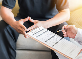 Male patient having consultation with doctor or psychiatrist who working on diagnostic examination on men's health disease or mental illness in medical clinic or hospital mental health service center
