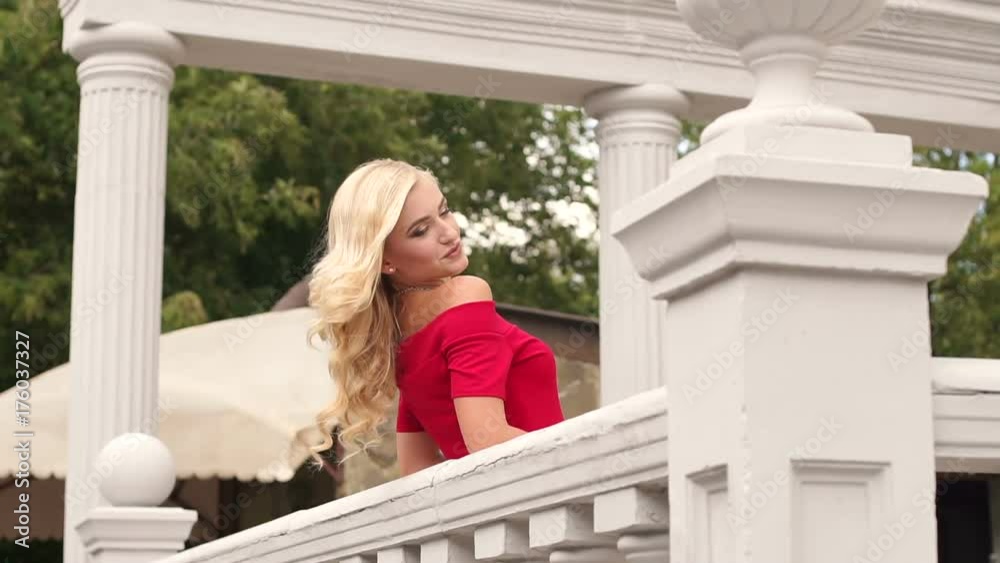 Beautiful young woman in red dress with long flowing hair stands ...