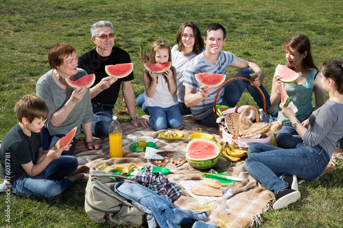 Family with children talking and eating watermelon