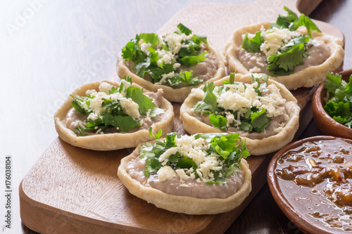Mexican sopes with cotija cheese and salsa on wooden surface photo