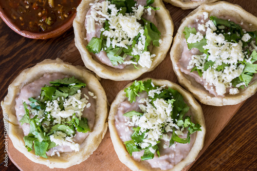 Mexican sopes with cotija cheese and salsa on wooden surface