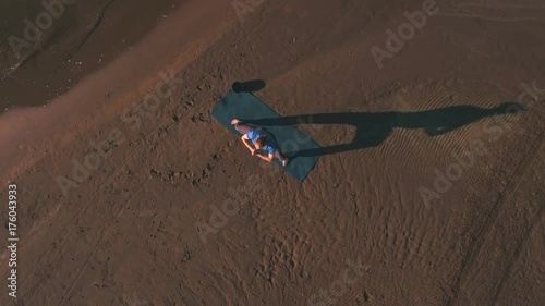 aerial view on a man does yoga on the beach at sunset photo