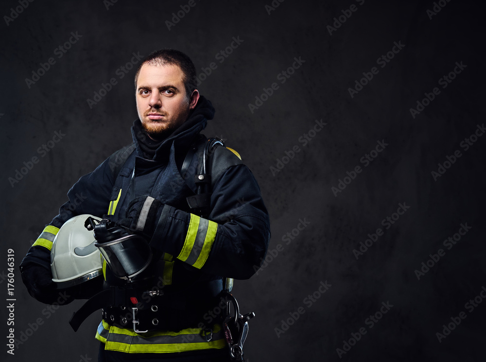 Fototapeta premium Firefighter dressed in uniform holds safety helmet.