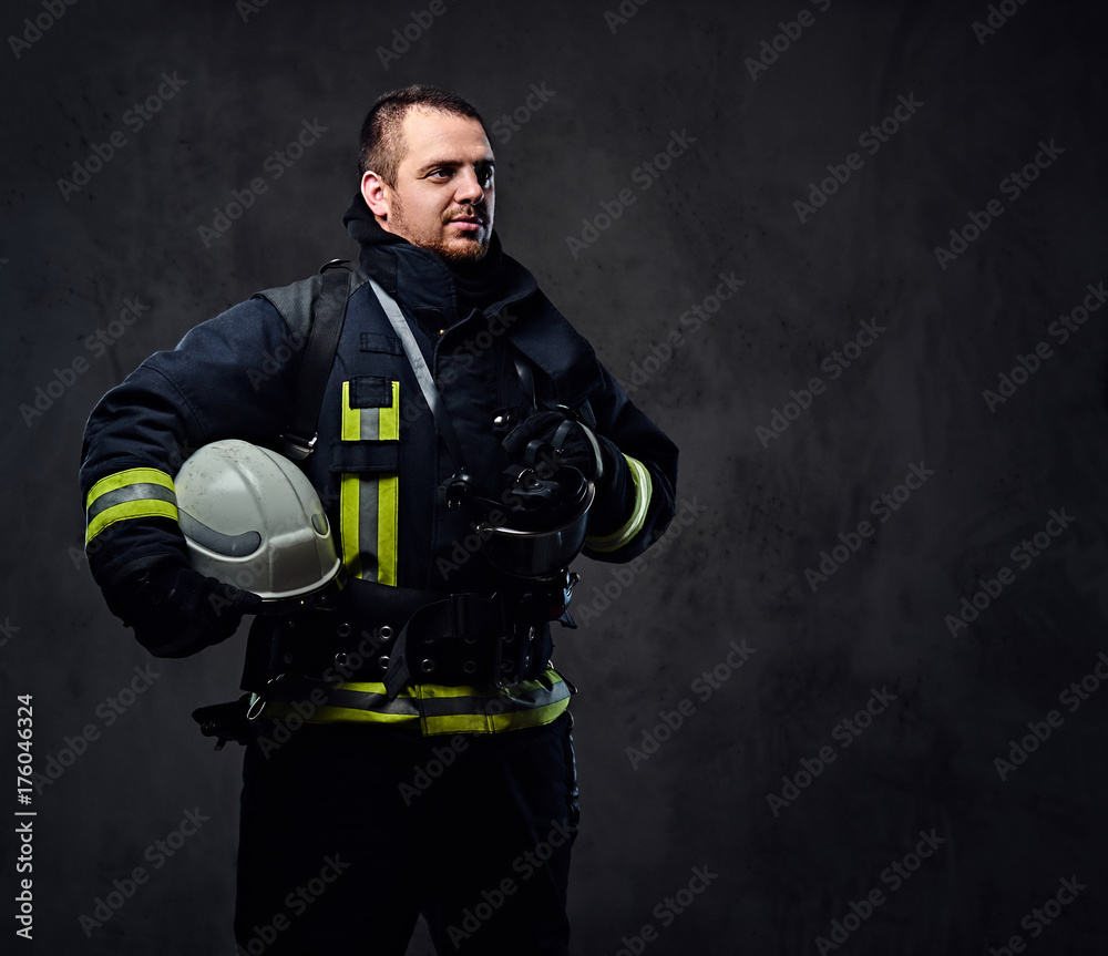 Fototapeta premium Firefighter dressed in uniform holds safety helmet.