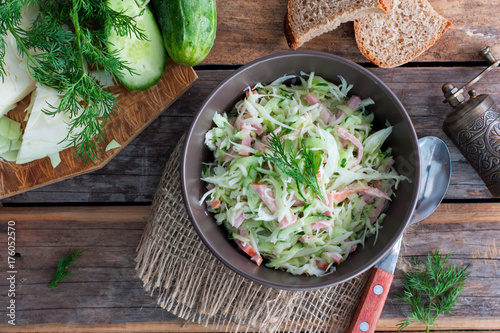 prepared salad with cabbage and ham on a wooden table, top view, horizontal