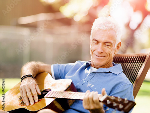 Senior man plying guitar outdoors