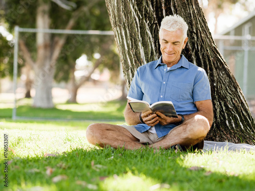 Senior man sittingin park while reading book photo