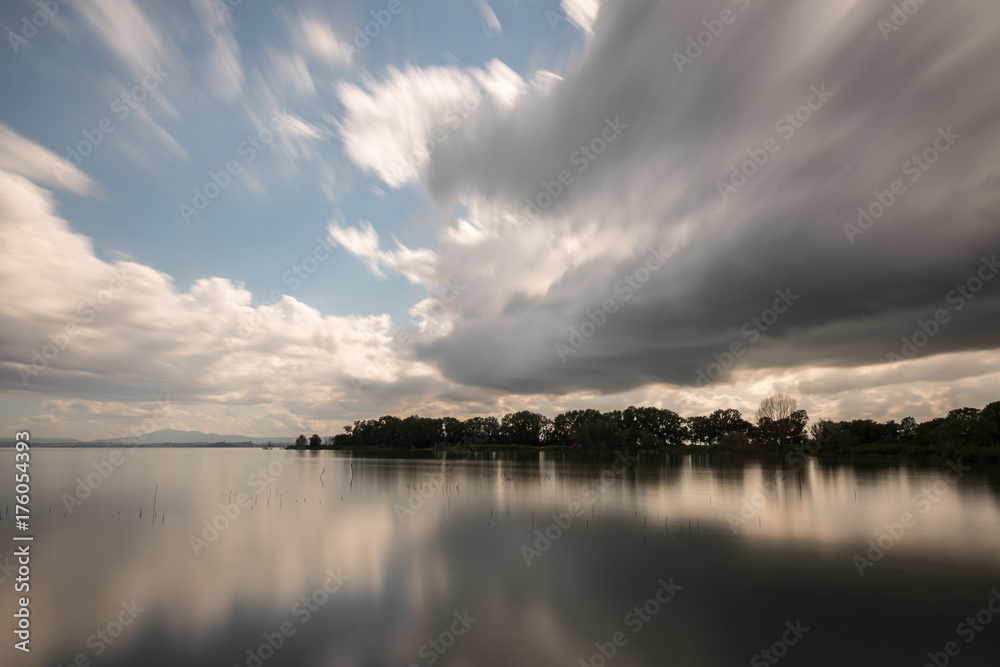 Long exposure view of a lake with moving white clouds perfectly reflecting on water