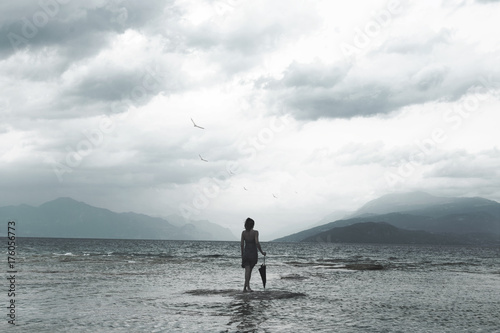 lonely woman looks at infinity and uncontaminated nature on a stormy day