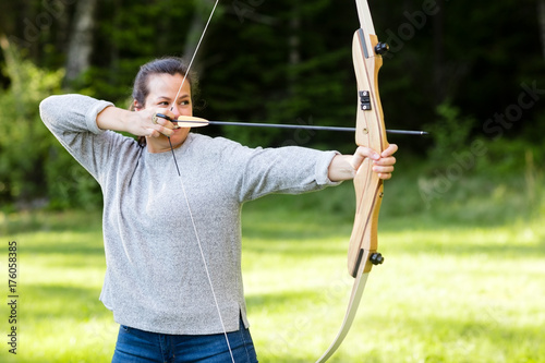 Female Archer Aiming With Bow And Arrow In Forest