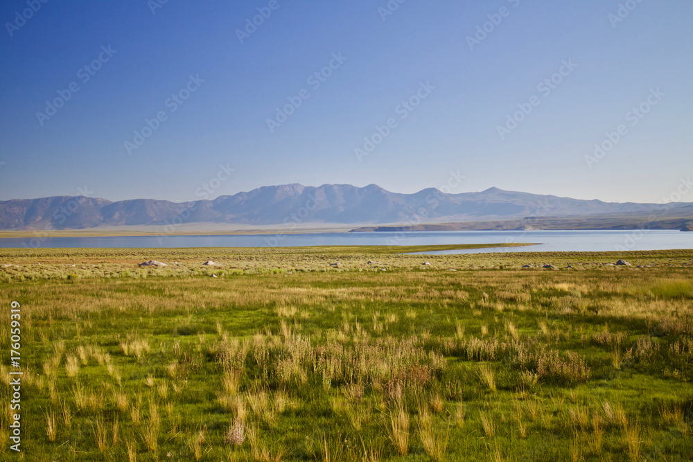 Lush grassy meadows / Vale lake surrounded by grassland with mountains in the back