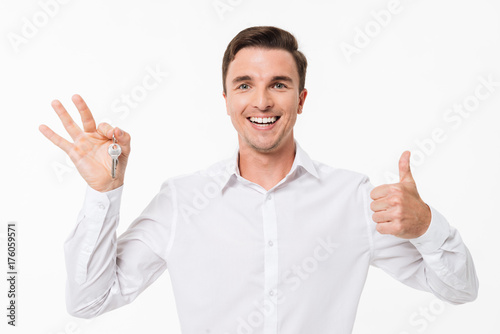 Portrait of a happy man in white shirt holding keys