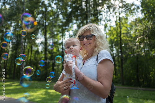 Child in mother s arms looking to the soap bubbles
