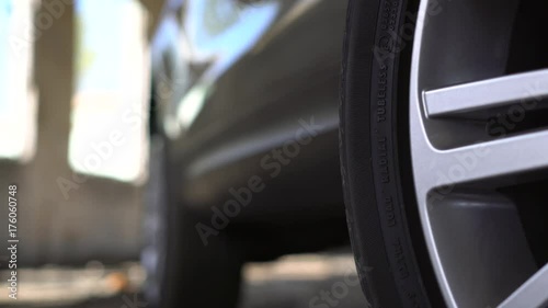 Close up detail view of modern parked car chrome rimmed wheel. Panning effect.