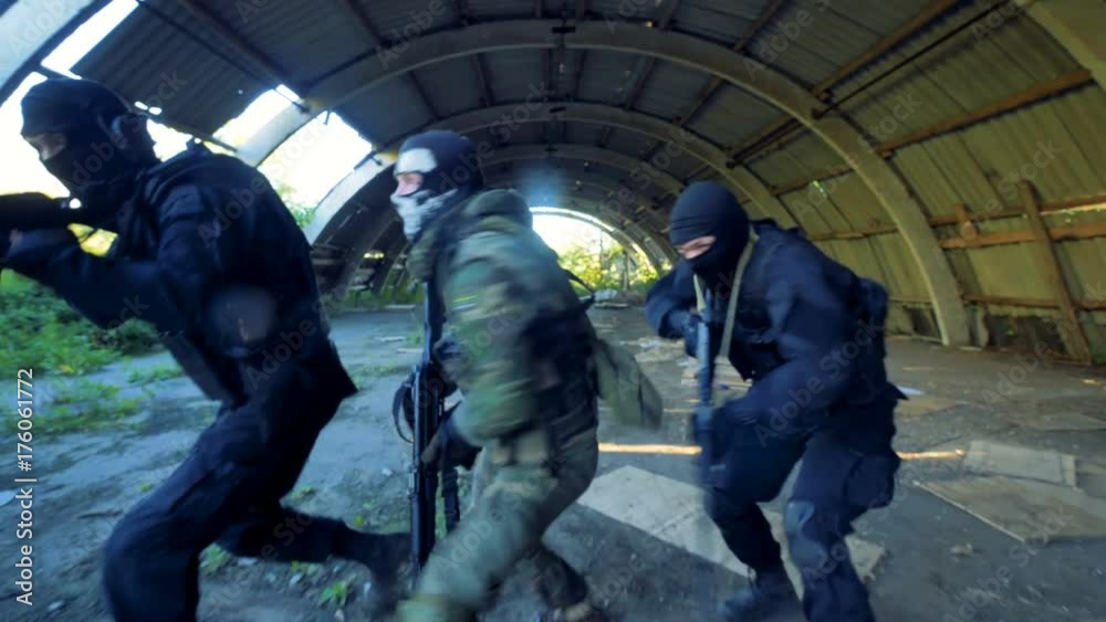 Three gunned men turn around during the military action. Three gunned men turn around during the military action.