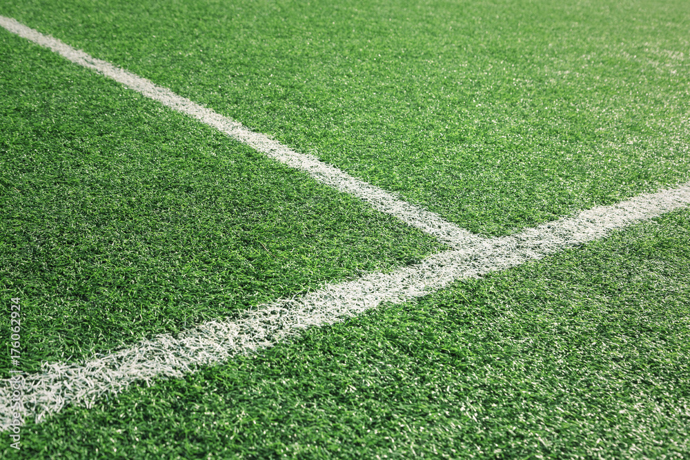 Artificial green soccer or rugby grass field with white intersection line. Selective focus used.