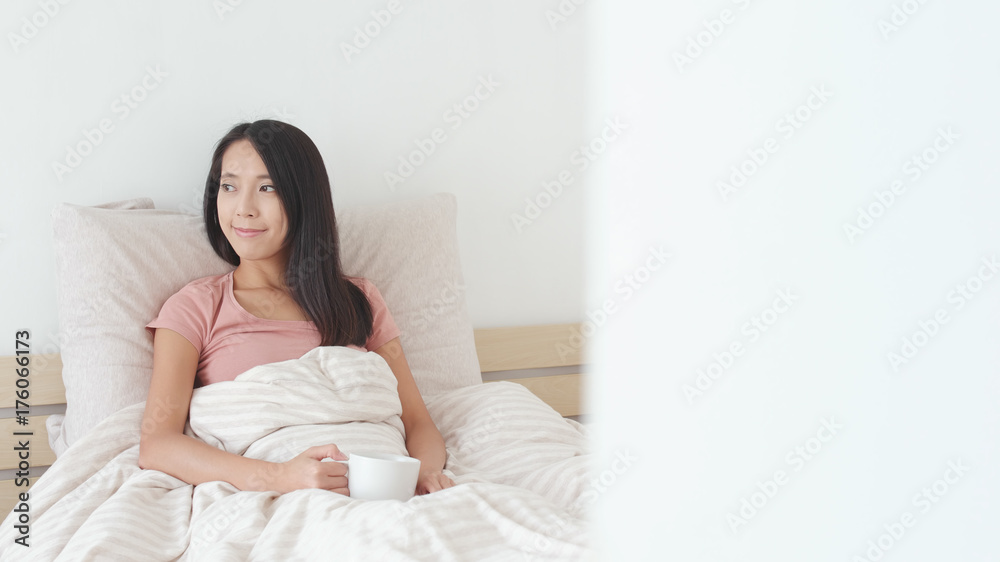 Woman holding a cup of tea on bed Woman holding a cup of tea on bed