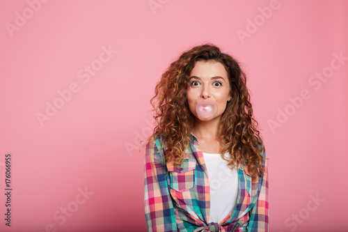Young lady blowing bubble gum isolated over pink photo