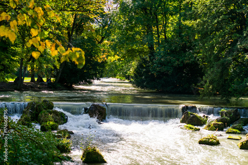 View of the Eisbach river waterfall during autumn in English Garden in Munich, Germany