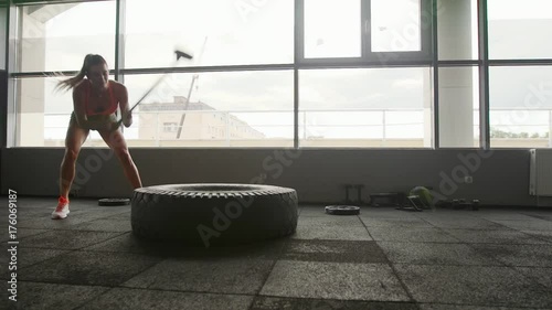 A woman lifts a large tire on an artificial turf field while working out exercising - fitness crossfit exercise workout