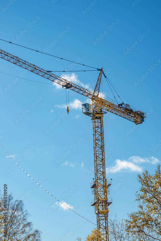 Construction crane on background of blue sky, cityscape in autumn