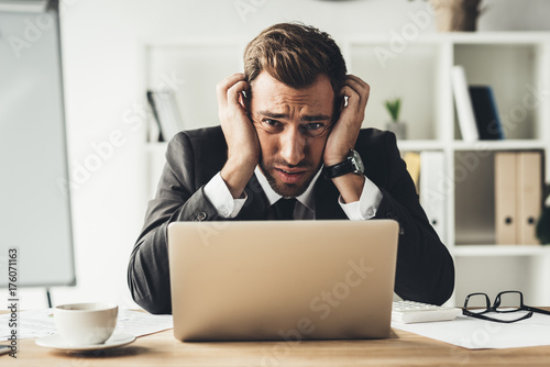 embarrassed businessman with laptop photo