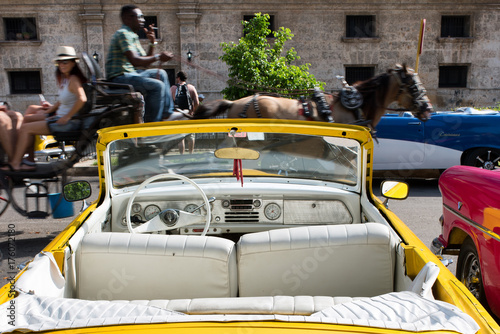 Photography Vintage american yellow car parked and coach passing by in Havana Cuba