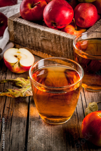 Fresh organic farm apple juice in glasses with raw whole and sliced red apples  on old rustic wooden table  copy space