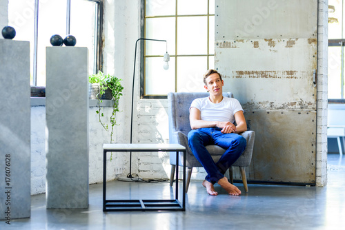 A young handsome man relaxing in a armchair in a loft style apar © Spectral-Design