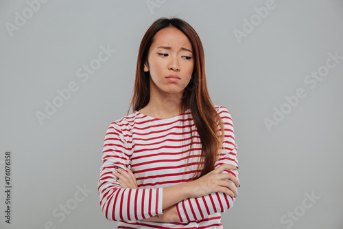 Portrait of a sad asian woman standing with arms folded