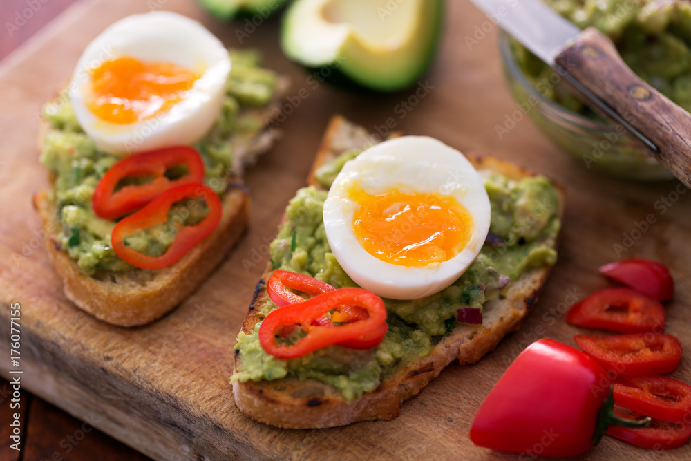 Healthy breakfast- sandwich prepared with guacamole, pepper and boiled chicken egg on the wooden chalkboard Healthy breakfast- sandwich prepared with guacamole, pepper and boiled chicken egg on the wooden chalkboard