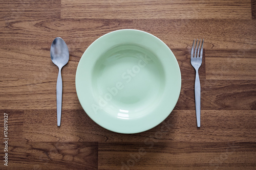 Empty Green Dish with Stainless Forks and Spoon, on Wood Texture Background