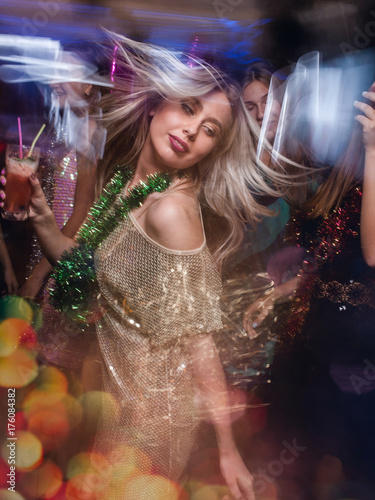 Female in night club in blurred motion. Stylish lady at Christmas discotheque, New Year company, modern youth life