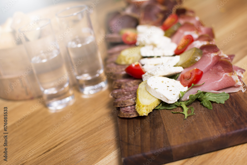 Mediterranean olives, sun-dried tomatoes, baguette slices, camembert cheese and spices on wooden background. Sausage and prosciutto slices on a wooden board. Appetizers served at an event.
