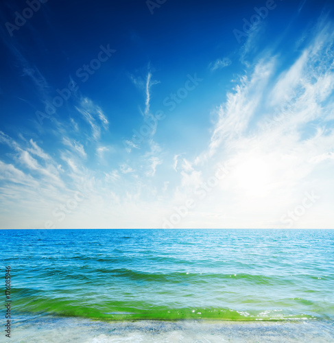 blue sky with clouds and sun over sea