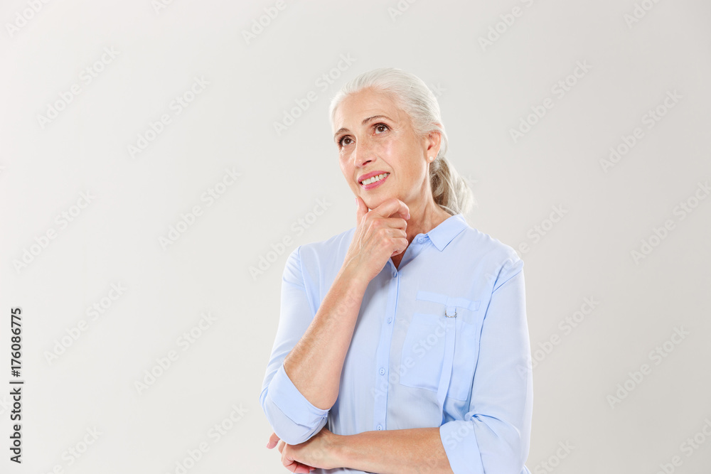 Portrait of dreaming cheerful old lady, touching her chin, looking aside Portrait of dreaming cheerful old lady, touching her chin, looking aside