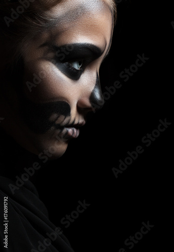Closeup profile of a girl with make-up skeleton. Halloween portrait. Isolation on a black background