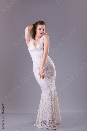 Curvy model with long hair, red lips wearing evening white dress. Plus size woman fashion.