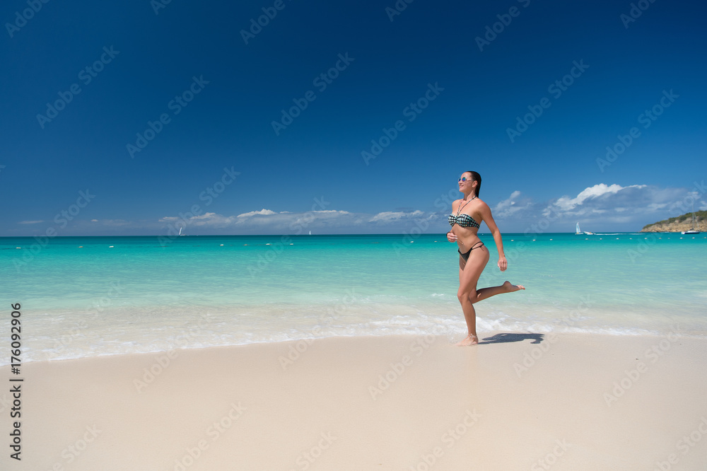 Girl in bikini running on sea beach
